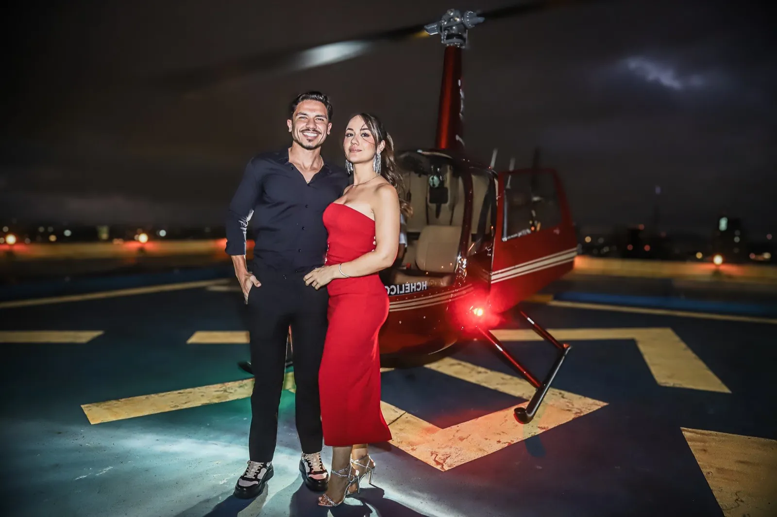 Casal em frente ao helicóptero High Class
